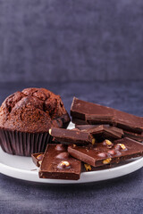 Chocolate cupcake with icing and chocolate bar in Dark lighting,Homemade delicious chocolate muffin on wooden background close-up