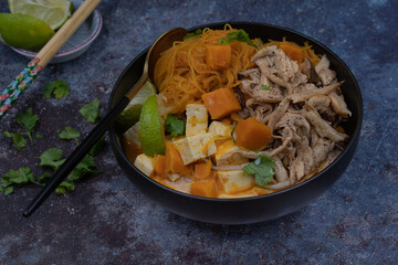 Rice noodles, sweet potato, tofu and king oyster mushroom simmered in vegan Thai red curry, copy space