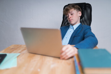 A mid shot of a serious Caucasian teenage boy in school uniform during his online classes. Online education concept