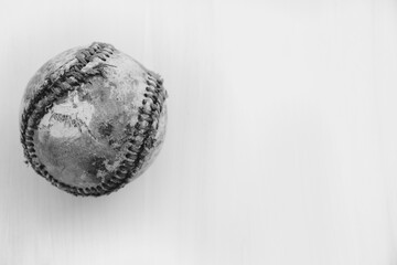 Old torn baseball with worn leather on white background.