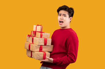 Excited asian guy holding stack of present boxes