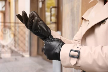Deurstickers Stylish man putting on black leather gloves outdoors, closeup © New Africa