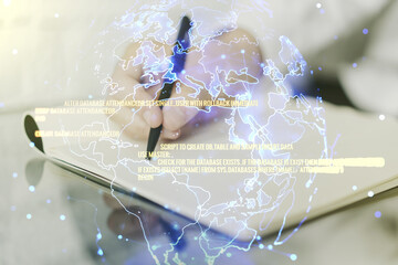 Double exposure of abstract programming language with world map and man hand writing in notebook on background, research and development concept