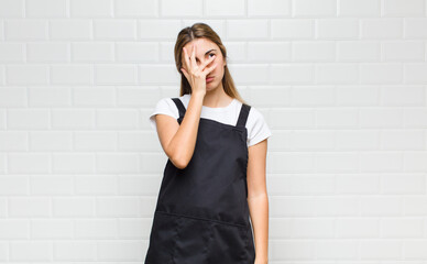 blonde woman feeling bored, frustrated and sleepy after a tiresome, dull and tedious task, holding...
