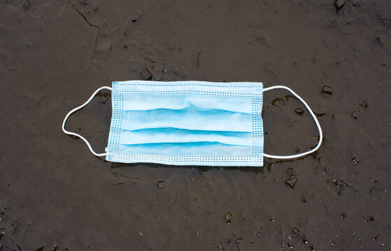 Medical Mask On The Ground In The Mud