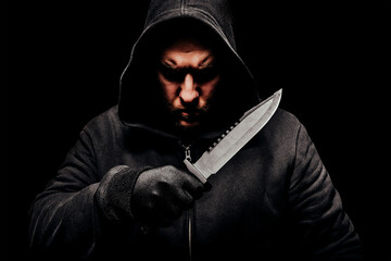 Horror scary photo of a dangerous creepy man in hoodie holding big hunting knife.