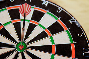 bullseye target or dart board has red dart arrow throw hitting the center