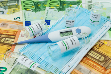 Coronavirus vaccines, surgical mask and digital thermometer on euro banknotes