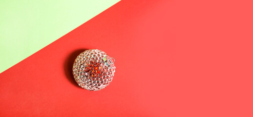 Red Christmas ball with transparent ice bumps on a red-green background with geometry and shadow. Space for text. Christmas, New year