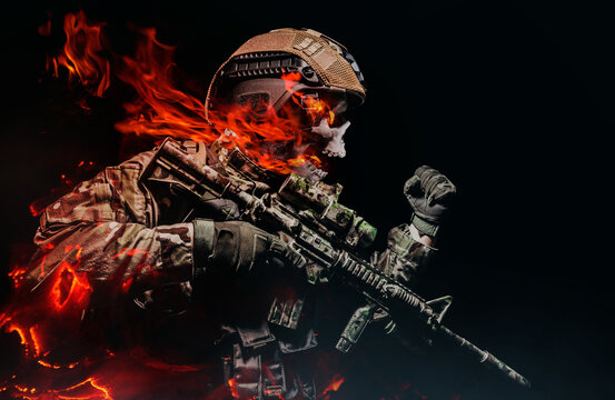 Photo of a fully equipped military burning skeleton soldier in armor vest with rifle attacking on black background.