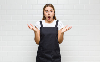 blonde woman feeling extremely shocked and surprised, anxious and panicking, with a stressed and...
