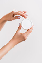 cropped view of woman holding container of hand cream isolated on grey, stock image