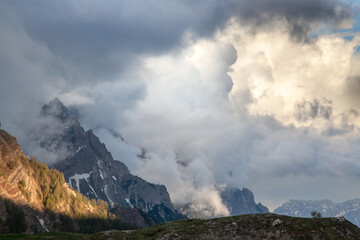 The mountain peaks of the Alps are shrouded in thick clouds. Evening light.
