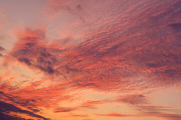 Fire sky background. Soft clouds with the hint of the sun at sunset. Many orange tones and patterns of clouds