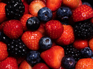 Detailed top view full frame heap of fresh fruit: strawberries, blackberries and blueberries.