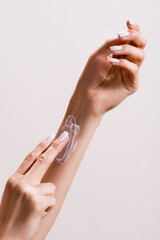 cropped view of woman applying hand cream on arm isolated on grey, stock image