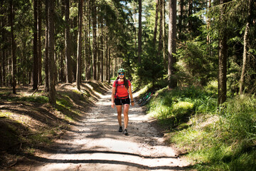 Obraz premium Young athletic woman with helmet is walking on the road in the forest.