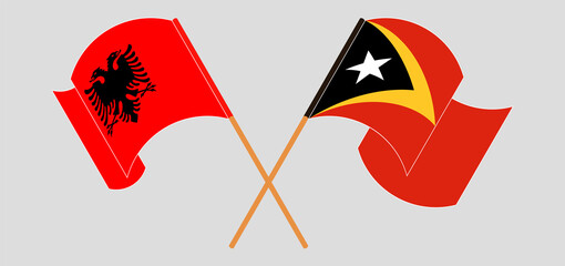 Crossed and waving flags of Albania and East Timor