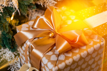 Holiday white gifts box with gold tape on background of Christmas tree bokeh, sun light