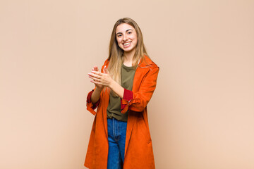 blonde woman feeling happy and successful, smiling and clapping hands, saying congratulations with an applause