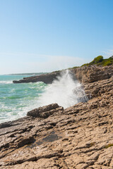 Obraz premium Beautiful waves crashing against a cliff. Sunny summer day with a wild ocean. Impressive and spectacular photography. Vertical photo.
