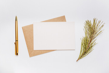 Blank note with envelope, spruce branch and gold pen on white background