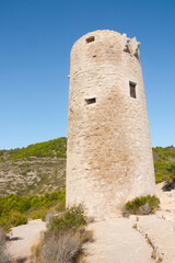 Medieval castle watchtower ruin. Torre Abadum or Badum tower. Beautiful protected Serra d'Irta Natural Park, Peniscola, Castellon province, Spain. Vertical shot.