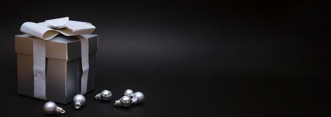 Silver gift box with christmas balls on black background
