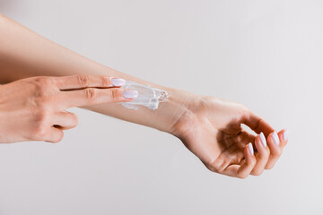 cropped view of woman applying hand cream on arm isolated on grey, stock image