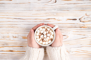 Comfort and relaxation concept. Top pov above overhead close up view photo of female hands holding cup full of tasty fresh hot cacao beverage on wooden white timber background