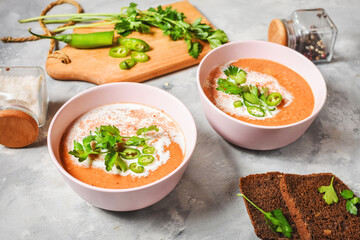 Red lentil tomato soup - delicious vegetarian food on concrte background. Healthy lunch