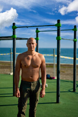 Physically fit man doing exercises on wall bars on morning beach