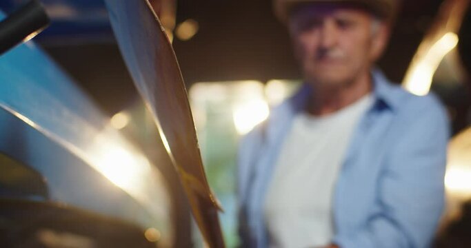 Close up shot of wooden paddle in old male hands. Caucasian senior man kayaker in hat turning and rotating oar that holding in hands indoors in sun lights. Summer sport concept