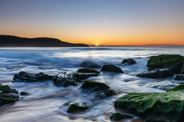 Sunrise by the Sea and Rocks on the Shoreline