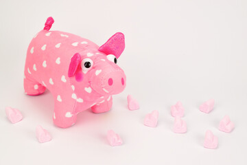 A soft toy in the form of a pig with white hearts. Sweets in the form of pink hearts are scattered around.