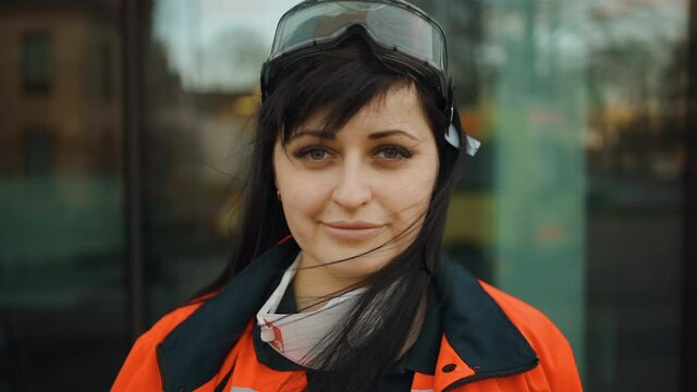 Smiling female paramedic with lowered respirator looks at you