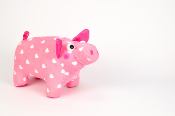 A soft toy in the form of a pink pig covered with white hearts, isolated on a white background.