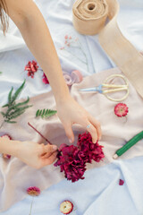 Obraz na płótnie Canvas close up of hands of a florist at work, pink hydrangea, flat lay, scissors, green fern 