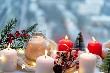 Winter Christmas holidays background with candles; christmas light; Cup of cocoa with marshmallow or hot chocolate near a window