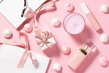 Creative composition with gift boxes, paper bags, candle, decorative cosmetic products and sweet meringue cookies on pink pastel background top view Christmas or Valentines Day background.