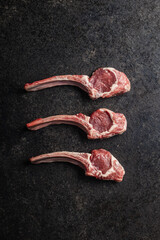 Slices raw lamb chops on black table.