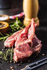Slices raw lamb chops on black table.