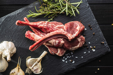 Slices raw lamb chops on black table.