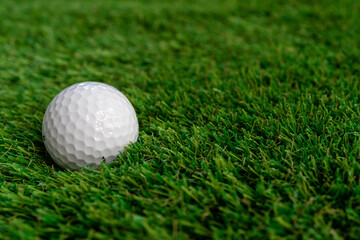 Golf ball on green artificial grass, top view with space for text - macro, selective focus, space for text