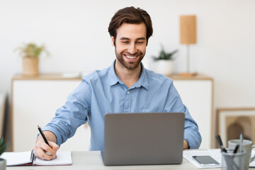 Cheerful Businessman Taking Notes Working At Workplace In Office