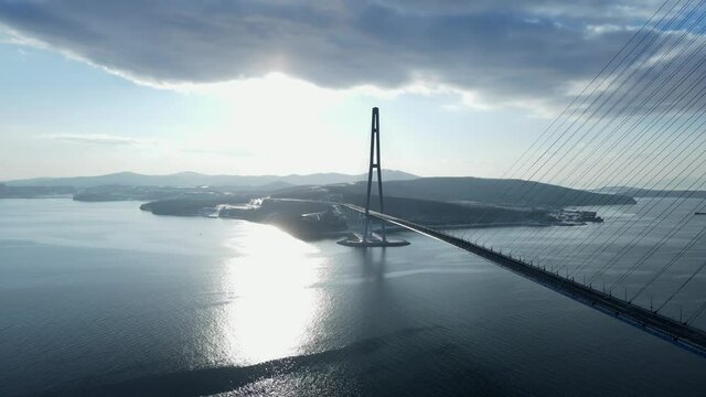 Top view of the Russian bridge. In the background is the Russky Island. Russia. The camera flies near the Russian Bridge in the winter during a bright sunset.