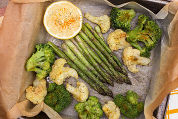 Baked vegetables asparagus, broccoli and cauliflower with spices and lemon on parchment paper close up. Vegan healthy diet food concept