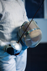 Child in a fencing suit with a sword in hand in the studio. Young boys practice and practice...