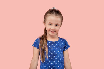 Portrait of a cute smiling beautiful girl looking at the camera on a pink isolated background. Blue dress with a small star.