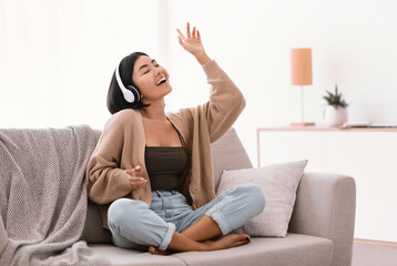Asian woman listening to music in headphones and dancing